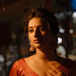 Elegant portrait of a woman in traditional ethnic attire, illuminated softly.